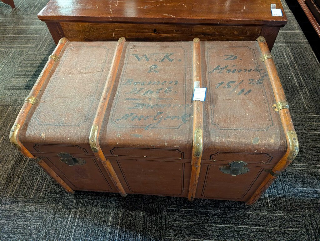 Antique Steamer Trunk / Travel Chest Antique steamer trunk featuring a brown textured exterior with decorative black line detailing, wood slat reinforcements, brass-tone corner and strap hardware, and two front latches. The interior retains its original s