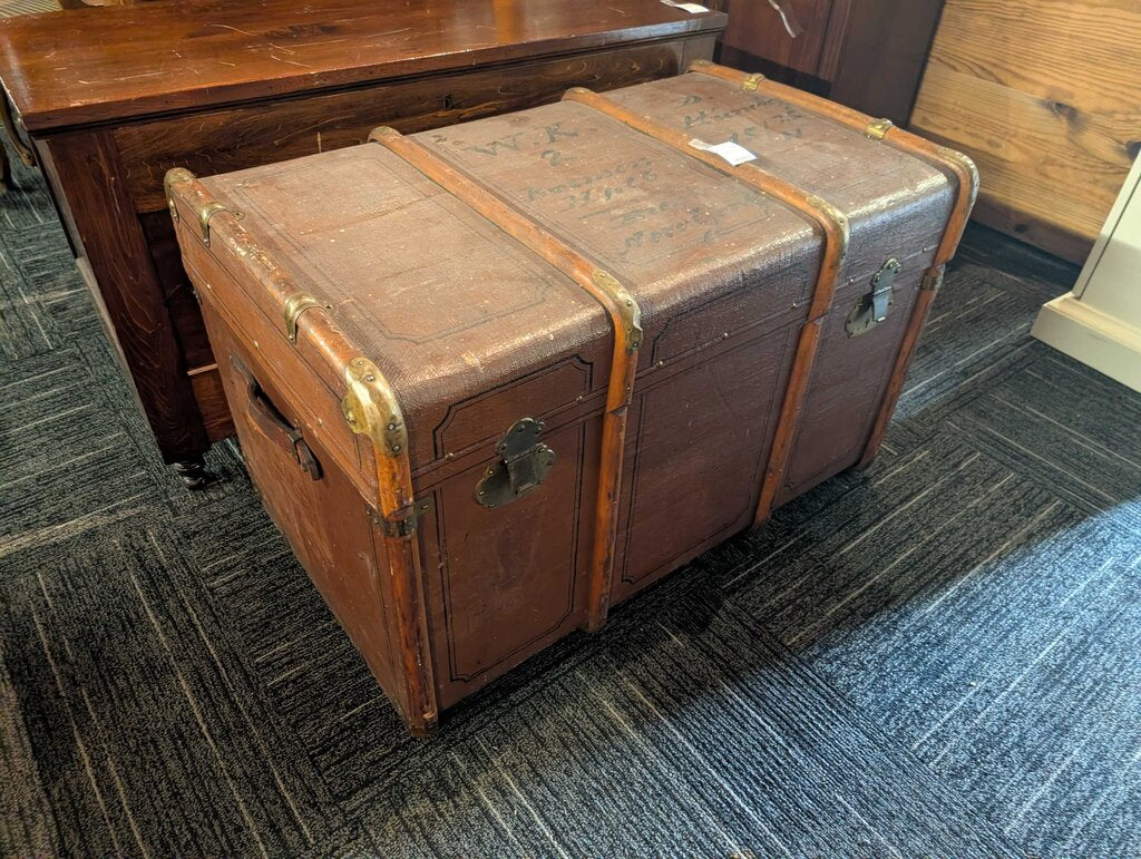 Antique Steamer Trunk / Travel Chest Antique steamer trunk featuring a brown textured exterior with decorative black line detailing, wood slat reinforcements, brass-tone corner and strap hardware, and two front latches. The interior retains its original s