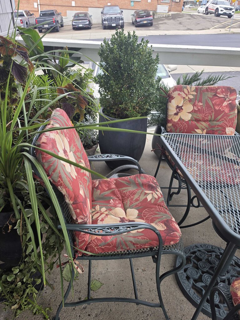 Wrought Iron Patio Table With Four Chairs And An Umbrella Stand