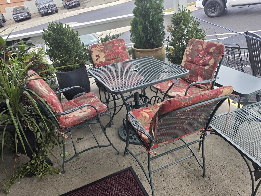 Wrought Iron Patio Table With Four Chairs And An Umbrella Stand