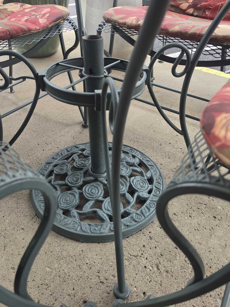 Wrought Iron Patio Table With Four Chairs And An Umbrella Stand