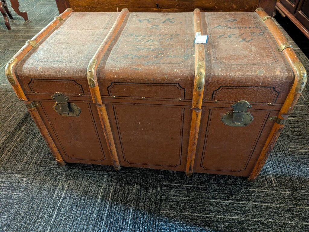 Antique Steamer Trunk / Travel Chest Antique steamer trunk featuring a brown textured exterior with decorative black line detailing, wood slat reinforcements, brass-tone corner and strap hardware, and two front latches. The interior retains its original s