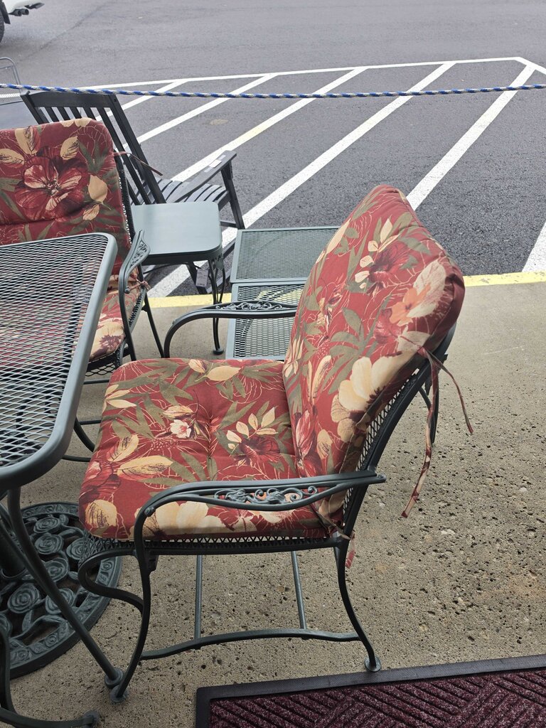 Wrought Iron Patio Table With Four Chairs And An Umbrella Stand
