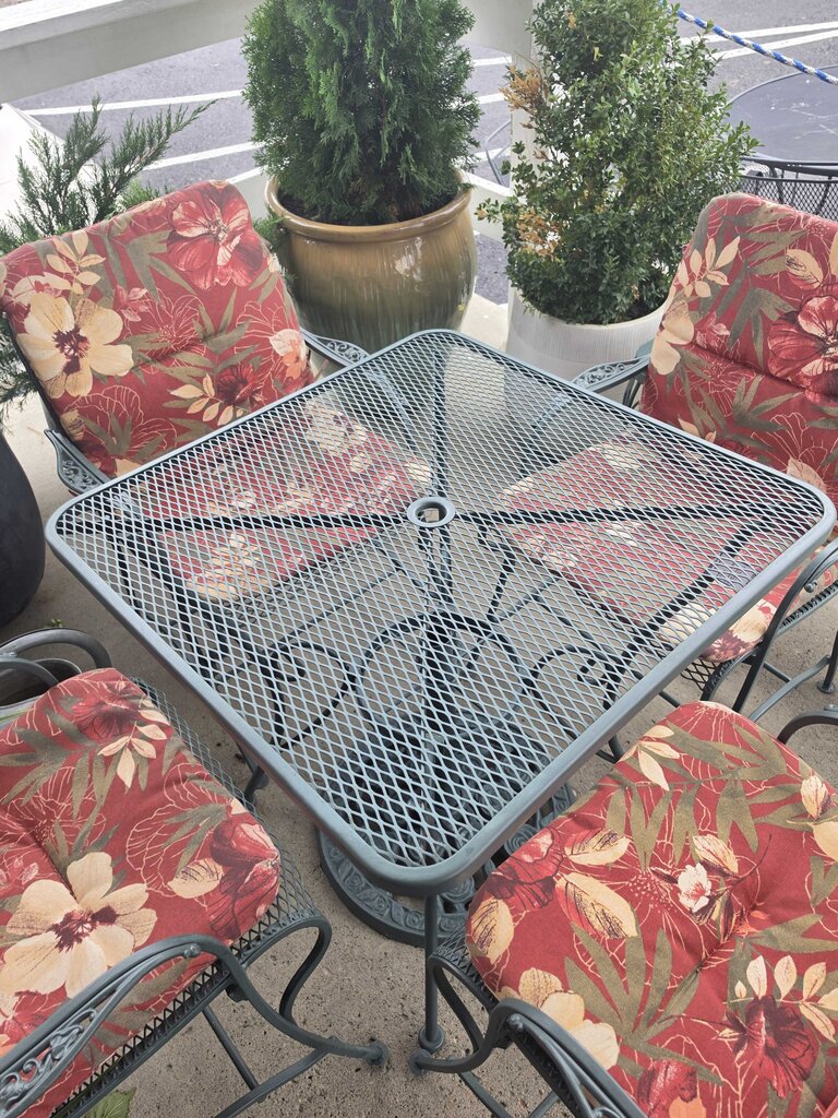 Wrought Iron Patio Table With Four Chairs And An Umbrella Stand