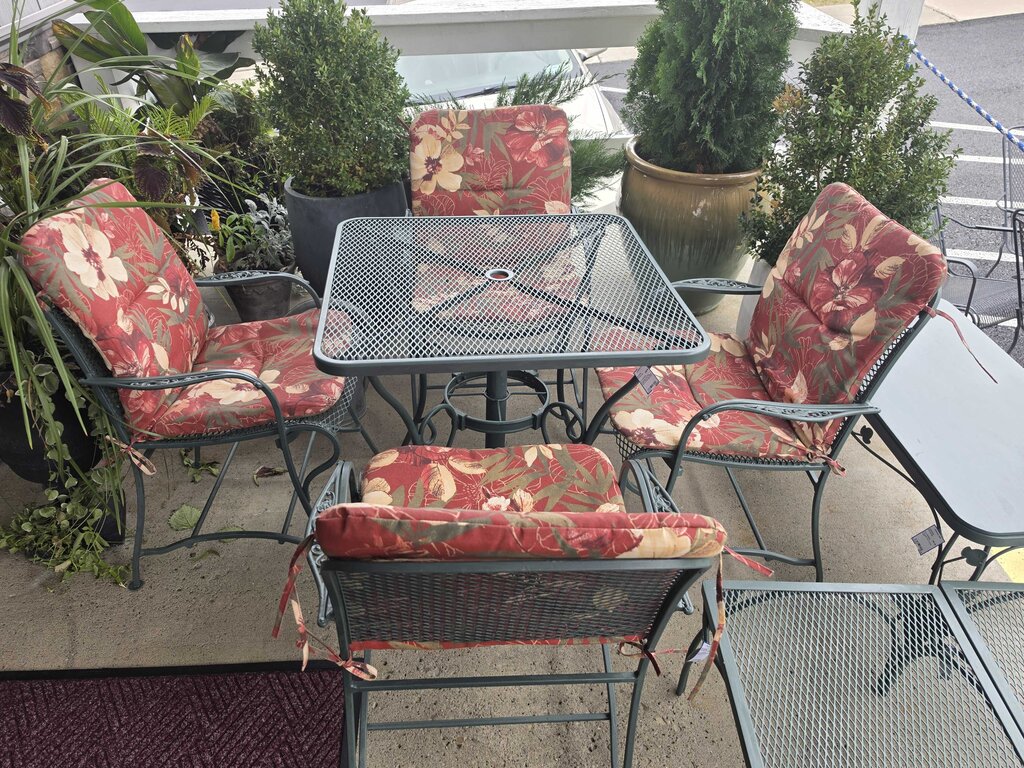 Wrought Iron Patio Table With Four Chairs And An Umbrella Stand